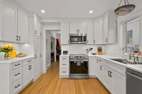 Malden, MA kitchen remodel with white shaker cabinets, a stainless range and microwave, and oak floors