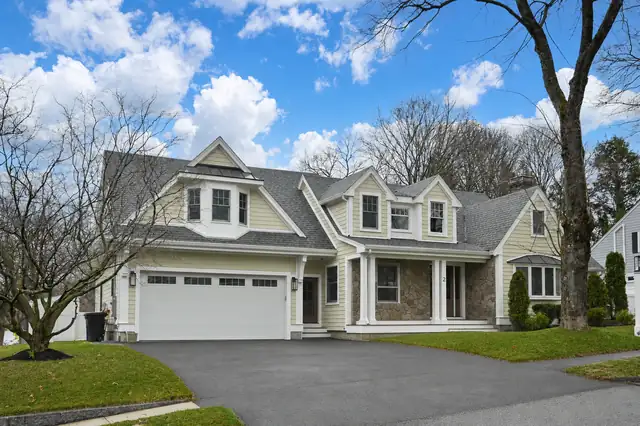 Two-story new construction home by Halco with gray siding, a front porch and an attached garage