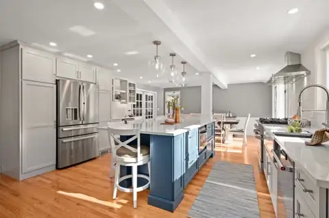 Topsfield, MA kitchen with a navy blue island, white cabinets, glass globe pendants and stainless appliances