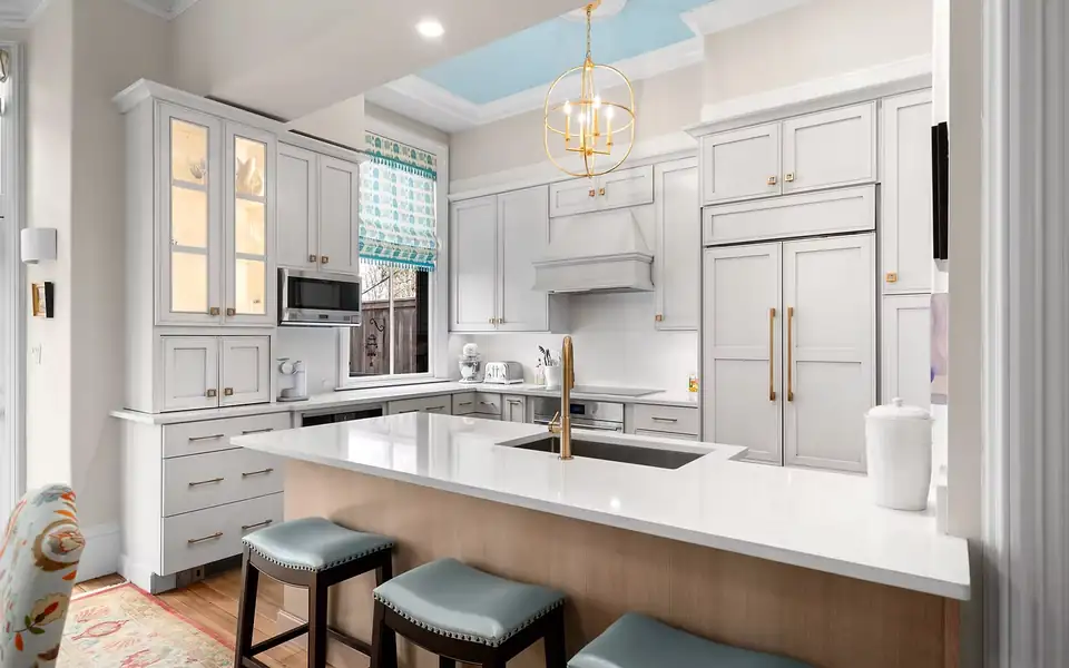 Kitchen remodeling Malden MA and Greater Boston: Halco's Brookline kitchen with white inset cabinets, glass-front uppers, a quartz island with blue-gray stools and a skylight