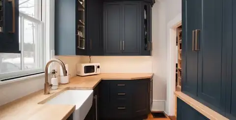 Lynnfield, MA built-in pantry with navy cabinetry, a butcher-block counter, farmhouse sink and brass faucet