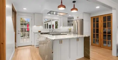 Beverly, MA kitchen with white cabinets, a white island, copper pendant lights and wood-framed French doors