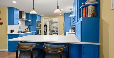 Melrose, MA kitchen with bright blue custom-color cabinets and island, white quartz counters and open shelving